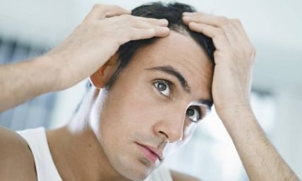 Man inspecting hair loss in mirror